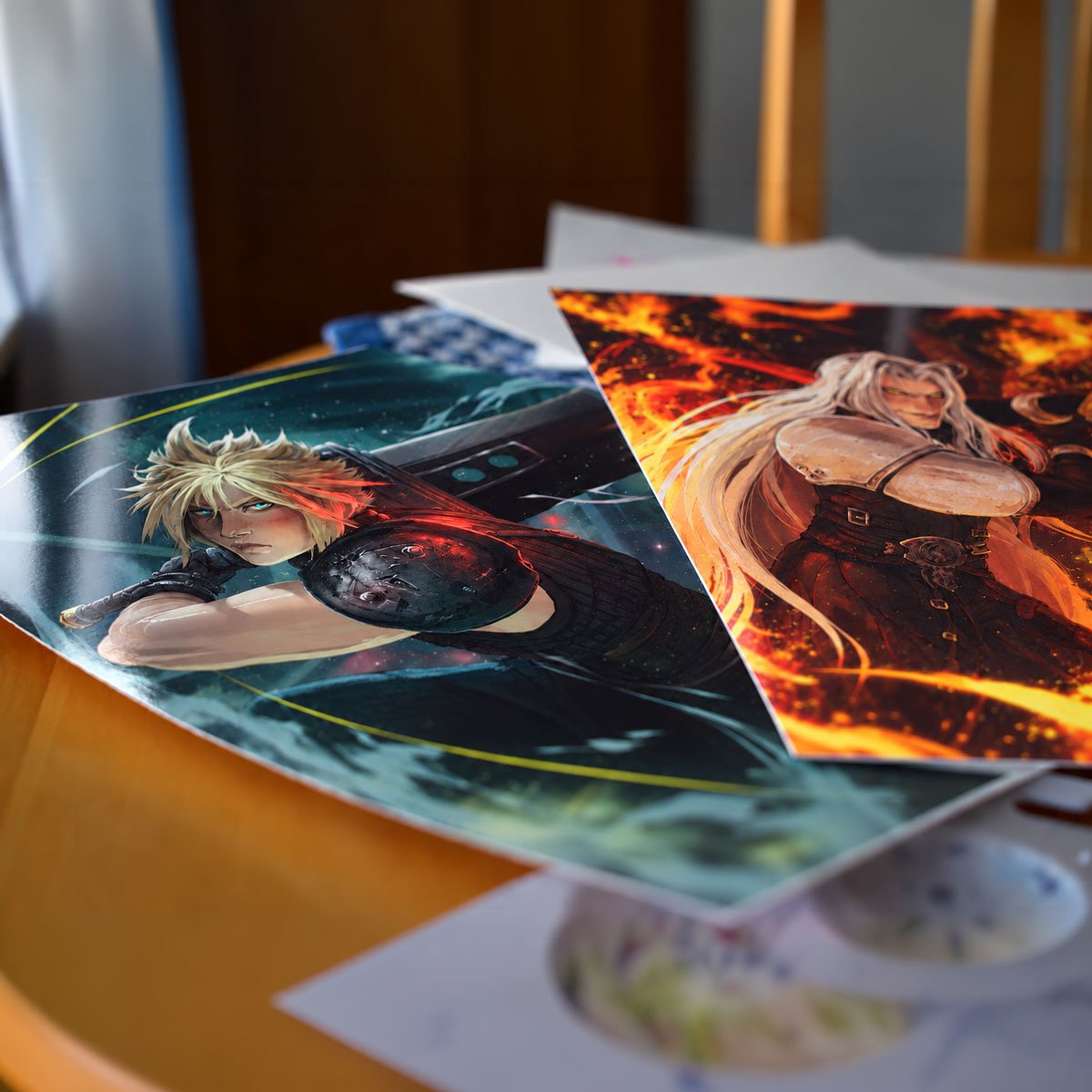 Two glossy Final Fantasy VII art prints are displayed side by side. Cloud Strife, with spiky blond hair and his Buster Sword, is surrounded by cool teal and blue tones, while silver-haired Sephiroth stands against swirling orange flames.